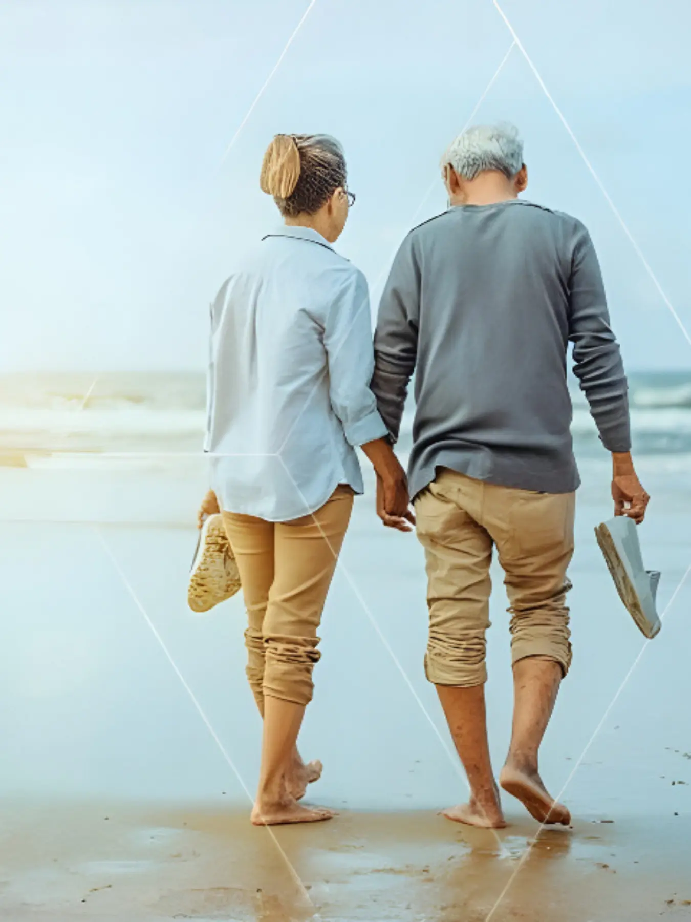 A senior couple walking along the shore, symbolizing the leisure and security achieved through long-term wealth preservation.