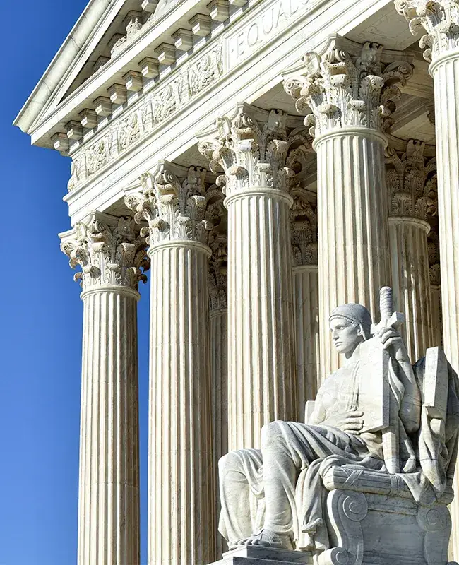 Neoclassical building with tall Corinthian columns and a seated statue in the foreground.