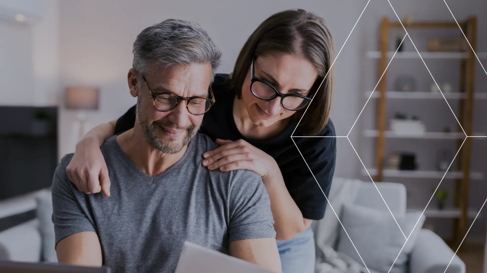 Couple reviewing financial documents together at a table with a laptop nearby.