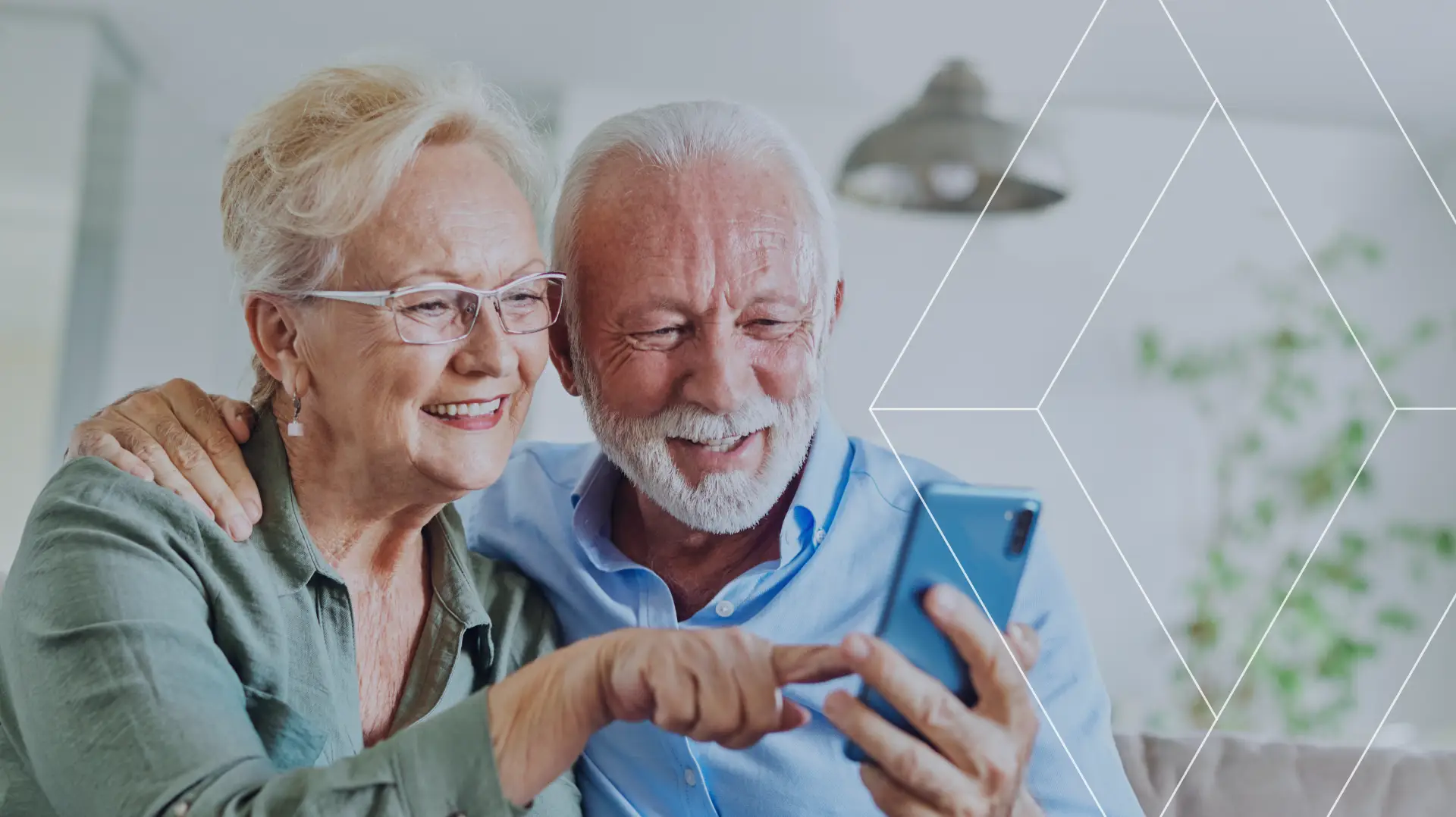 Older couple smiling while looking at a smartphone together at home.